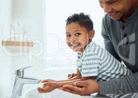 I love washing my hands with dad. an adorable little boy washing his hands with the help of his father at home.