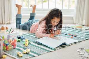 Its almost playtime. a little girl doing homework at home.