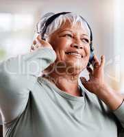 As this life gets colder, keep celebrating your own warmth. a beautiful senior woman listening to music while sitting on the sofa at home.