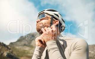 Safety first. a handsome mature man fastening his helmet while cycling outdoors.