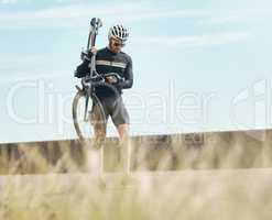 Looks like he may have a puncture. Full length shot of a handsome mature man carrying his bike while cycling outdoors.