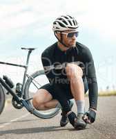 Its a long road. Make sure youre prepared. Full length shot of a handsome mature man tying his laces while cycling outdoors.