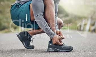 Im wearing my most comfortable running shoes. an athletic man tying his laces while our for a run.