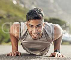 The more you do it, the more bearable it becomes. an athletic young man doing push-ups outside.