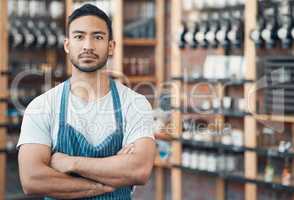 Portrait of one happy young hispanic waiter standing with his arms crossed in a store or cafe. Focused man and coffeeshop owner managing a successful restaurant startup