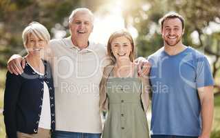 Portrait of a loving caucasian family with adult children standing together in nature on a sunny day. Happy senior couple posing outdoors with their daughter and son in law