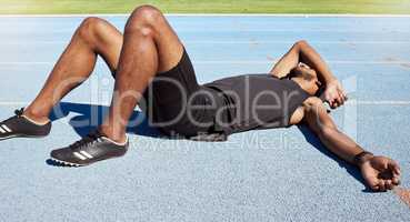 Closeup of a fit active young male athlete lying exhausted flat on the track after a race and feeling tired after a sprint on a running track. Male lacking energy after a hard workout practice run