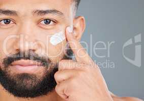 Making sure to lotion everyday. Studio portrait of a handsome young man applying lotion to his face against a grey background.