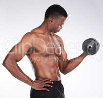 Heres to bigger arms. a young man standing alone in the studio and using a dumbbell for a bicep curl.