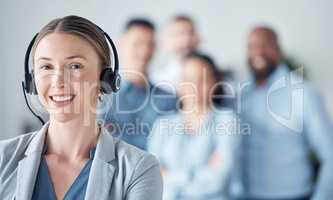 Problem solving comes naturally to customer care specialists. Portrait of a young call centre agent standing in an office with her colleagues in the background.