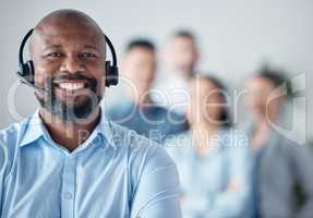 Maintaining a high customer satisfaction rate. Portrait of a mature call centre agent standing in an office with his colleagues in the background.