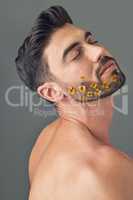 Want to grow a more fuller beard. Studio shot of a handsome young woman posing with flowers in his beard.