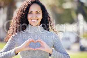 Ive got nothing but love for this world. an attractive young woman standing alone outside making a heart-shaped gesture.