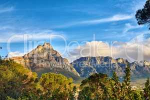 Copy space with scenic landscape of cloudy sky covering the peak of Table Mountain in Cape Town on a sunny morning from below. Beautiful views of plants and trees around an iconic natural landmark