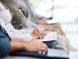 Unknown group of diverse businesspeople sitting together in the office for training. Team of colleagues using notebooks and paperwork while learning in a workshop. Attending a seminar for marketing