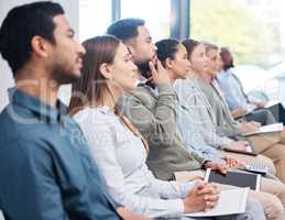 Diverse group of serious business people sitting together in office training. Focused team of colleagues using notebooks and technology while learning in a workshop. Attending a seminar for marketing