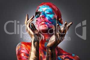 I dont want to be average. an attractive young woman posing alone in the studio with paint on her face and body.