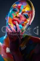 Color is powerful and directly influences the souL. Studio shot of a young woman posing with multi-coloured paint on her face.