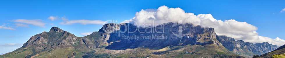 Panoramic landscape of the majestic Table Mountain and Lions Head in Cape Town, Western Cape. A cloudscape sky with copy space over large mountainous and hilly terrain in wonderful nature