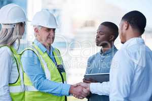 Building a great team is down to patience. a team of builders shaking hands in greeting.