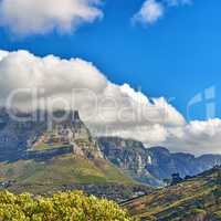 Thick clouds rolling over Table Mountain, Cape Town with copyspace. Cloud shadows passing rocky terrain on sunny day, beautiful, peaceful nature in harmony with soothing view of plants and landscape