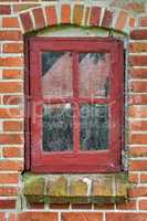 Closeup of abandoned red window covered in spiderwebs, algae and moss from neglect, poverty and economic crisis. Empty, old residential building or home in a village with damp mold on the windowsill