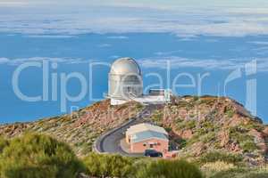 Roque de los Muchachos Observatory in La Palma. A road to an astronomical observatory with blue sky and copy space. Telescope surrounded by greenery and located on an island at the edge of a cliff.