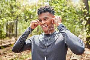 Young mixed race hispanic fit male athlete listening to music while on a run in a forest outside in nature. Exercise is good for health and wellbeing. Enjoying, positive, happy