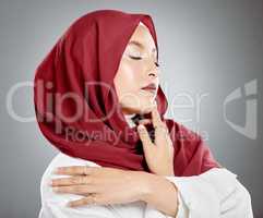 Beautiful muslim woman posing in studio wearing hijab. Headshot of stunning confident arab model standing against grey background. Fashionable woman wearing a headscarf. Elegant female in a headwrap