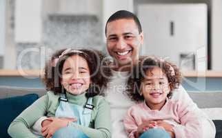 Childhood is such a precious time to cherish. Portrait of a father bonding with his two little daughters at home.