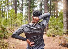 Unrecognizable mixed race hispanic male stretching before a run while experiencing some back and neck pain in a forest. Exercise is good for your health and wellbeing. Stretching is important to prevent injury and muscle strain