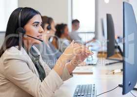 Would you like me to explain that again. a young call centre agent working in an office with her colleagues in the background.