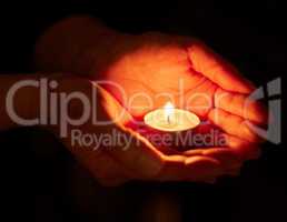 Hope can be a powerful force. a unrecognizable person holding a candle in the dark.