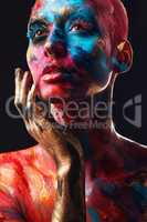 Art captures the soul. an attractive young woman posing alone in the studio with paint on her face and body.