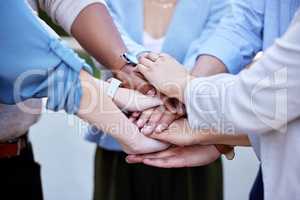 Helping each other achieve greatness. a group of business people with their hands stacked.