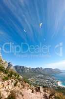People paragliding from a mountain with a scenic view in summer. Tourists having fun and doing adventurous activities while on holiday in a clear blue sky. People hand gliding from a cliff in nature