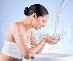 Happiness is a habit. So is your skincare. a young woman washing herself against a blue background.