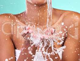 Wake up, wash up. an unrecognisable woman cupping her hands to catch water against a blue background in the studio.