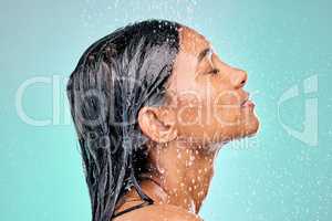 Skin care must be good enough to eat. an attractive young woman showering against a blue background.