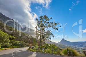 Roadtrip through mountain view landscape on tar road or street with blue sky during summer in Cape Town, South Africa. Travel and leading to scenic, lush green hills for weekend exploring and driving
