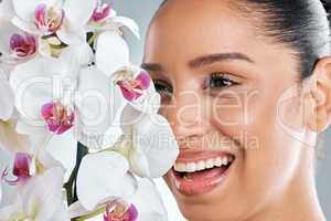 Natural is better, organic is best. Studio shot of an attractive young woman holding orchids against a grey background.