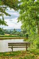 A bench overlooking a lake in the countryside, surrounded by farmland and a forest close to Lyon, France. A quiet place to relax and reflect. Find some peace and tranquility outside in nature