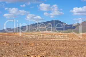 Farmland in the Western Cape of South Africa in the middle of the day. A mountain in a bare land with a cloudy blue sky. An empty farm with a nature view and a copy space.