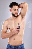 When people get my scent, I want it to linger. Studio shot of a handsome young man spraying deodorant on his armpit.