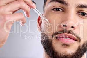 Its really not that much effort to take proper care of yourself. a handsome young man applying serum to his face with a dropper.