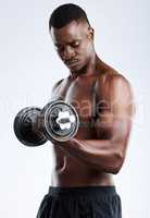 Building those biceps. Studio shot of a handsome young muscular man working out with a dumbbell against a grey background.