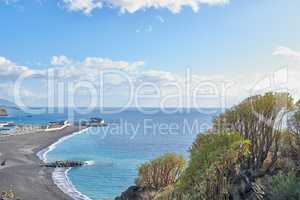 Scenic seaside and seascape of touristic coastal city of Puerto de Tazacorte in La Palma, Spain during summer. Landscape view of a sea with a black sand beach, a blue sky with clouds and copy space.