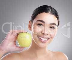 Add an apple to your everyday diet. Studio portrait of an attractive young woman posing with an apple against a grey background.