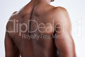 A back that can carry any load. an unrecognizable musclar man posing in studio against a grey background.