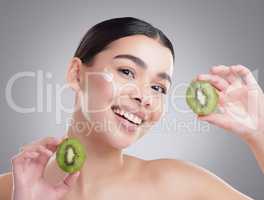Its a great source of fibre. Studio portrait of an attractive young woman posing with two halves of a kiwi against a grey background.